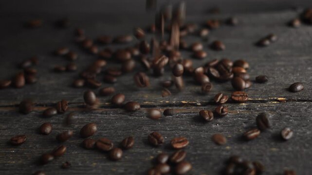 Freshly brewed coffee beans cascading onto a mysterious, aged wooden tabletop. An organic, premium ingredient to kickstart your day