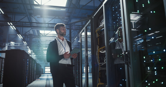 Technician uses tablet in a data center to analyze the server.
