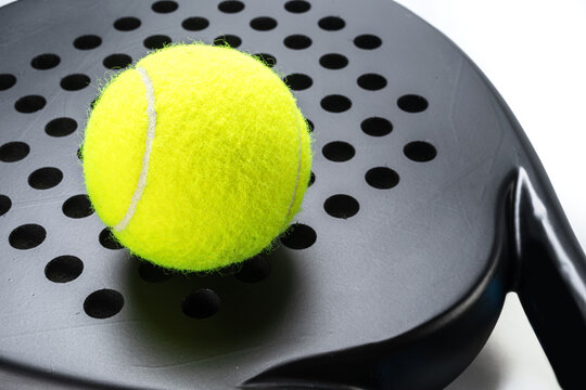 Close up, a padel ball lies on a black padel racket.