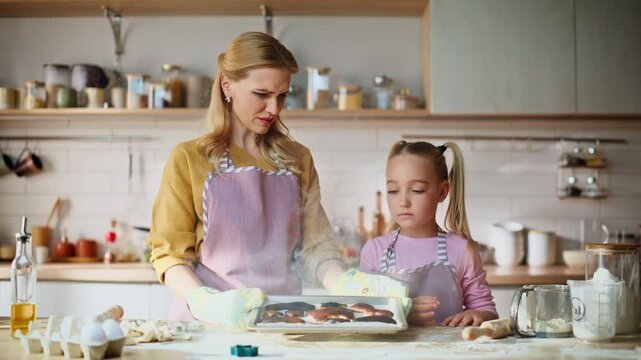 Mom daughter overcooking cookies home closeup. Frustrated family feeling unhappy