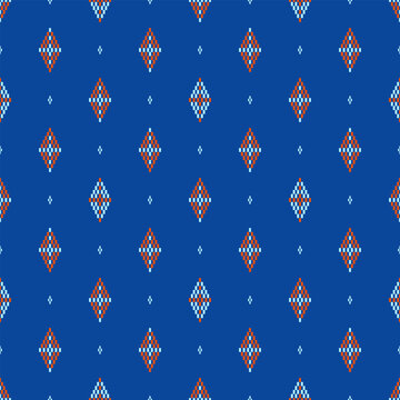 Seamless pixel geometric pattern with diamond motifs in orange and light blue on deep blue background. Repeating grid layout suitable for fabric, wallpaper, and surface design.