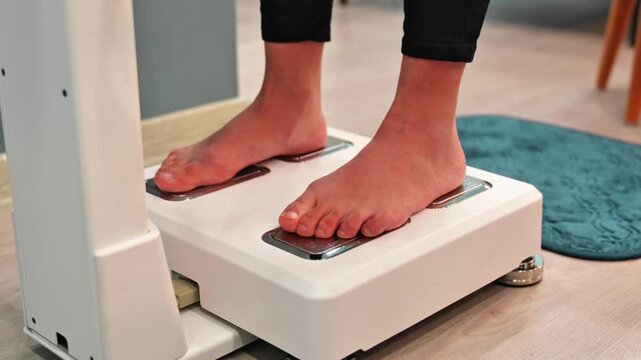 Person stepping onto weighing scale from blue mat, checking body weight at home close up