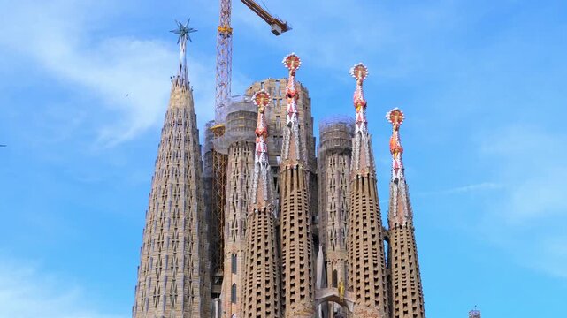 The famous and beautiful cathedral Sagrada Familia by architect Antonio Gaudi, Barcelona, Catalonia. Bottom view against a blue sky with white clouds. Copy space