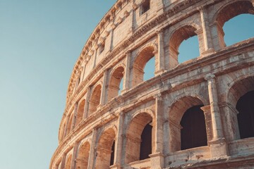 Fototapeta premium Massive ancient stone amphitheater structure rises against a clear pale blue sky