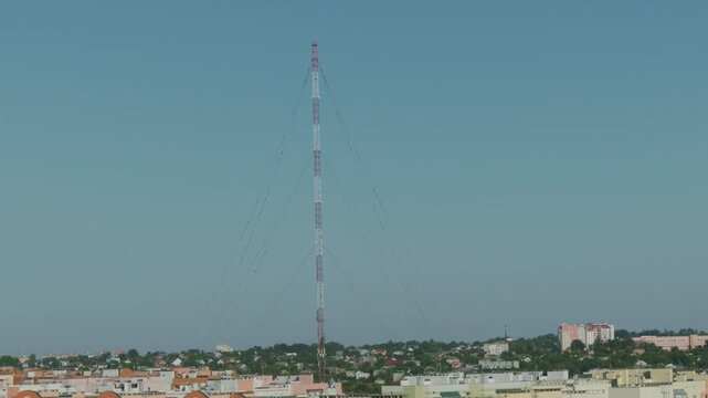 Tall radio tower structure against a clear blue sky over a cityscape