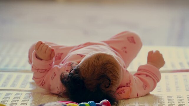 Baby lying on a play mat surrounded by colorful toys during playtime