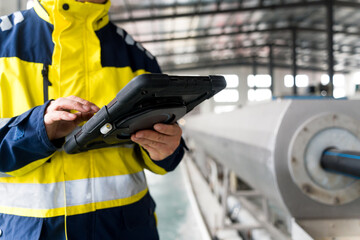 Worker in high-visibility jacket operating rugged industrial tablet in factory setting © zhu difeng