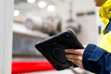 Worker holding industrial tablet to inspect equipment in factory setting © zhu difeng