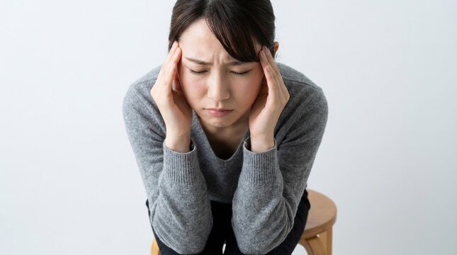 Stressed young japanese woman suffering from a severe headache or migraine, holding her head with copy space