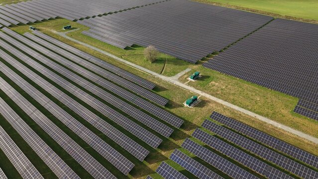 Aerial view of endless rows of solar panels contrasting with green grass and a solitary tree create a captivating geometric landscape, Newark, United Kingdom.