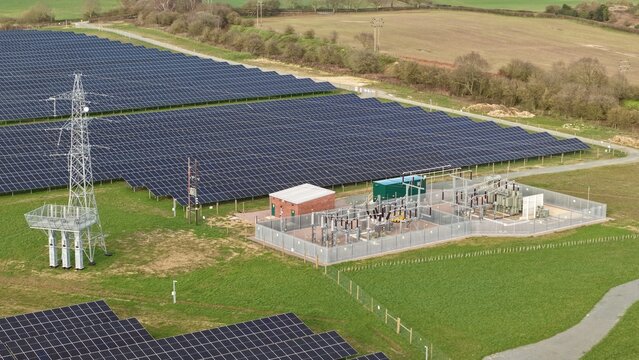 Aerial view of rows of gleaming solar panels contrast with the verdant fields and the functional architecture of the Goldbeck Solar Crifton South solar farm, Newark, United Kingdom.