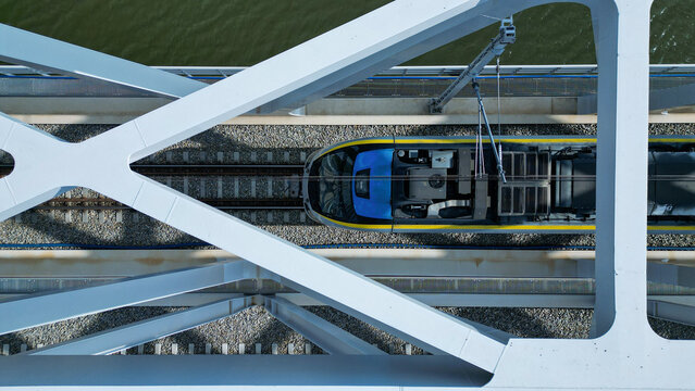 A modern iron railway bridge on a sunny day, seen from above