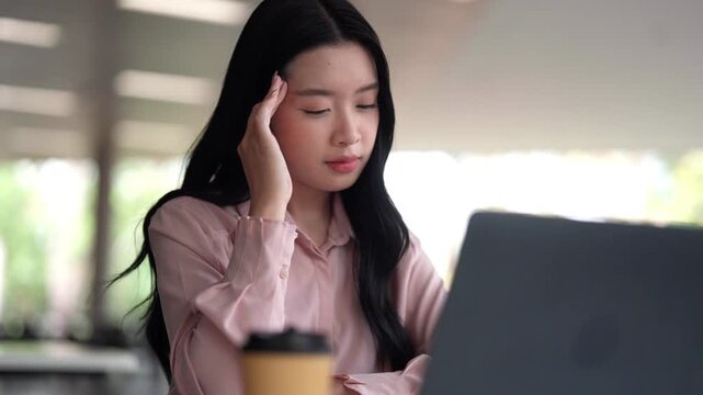 Asian young adult woman professional working on laptop computer digital device concentrating at modern cafe remote workspace