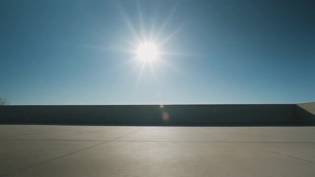 雲一つない空と燃えるような太陽の下、長く硬い影が伸びる広大なコンクリートの広場
