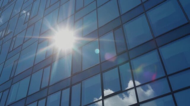青空と熱気を反射し強い太陽光のまぶしさを放つ大型オフィスのガラスファサード