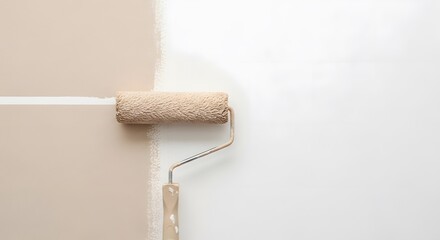 Obraz premium A paint roller applying a fresh coat of white paint over a smooth beige wall surface indoors