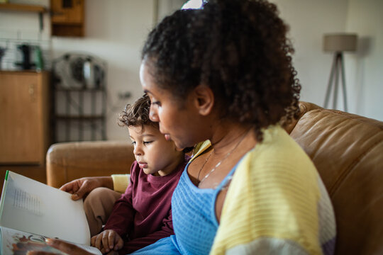 Mother reading storybook with son at home