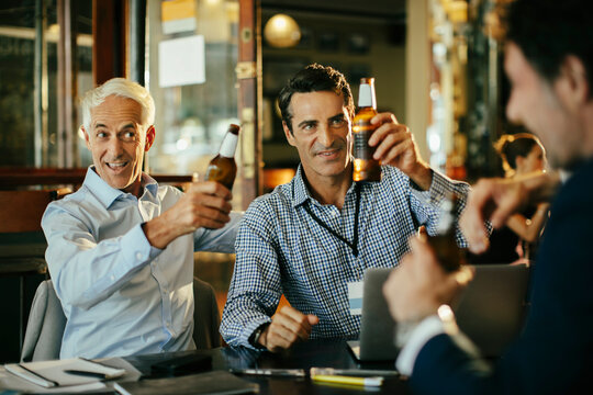 Business colleagues toasting with beers at a bar after work