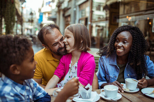 Smiling family enjoying coffee at outdoor street cafe