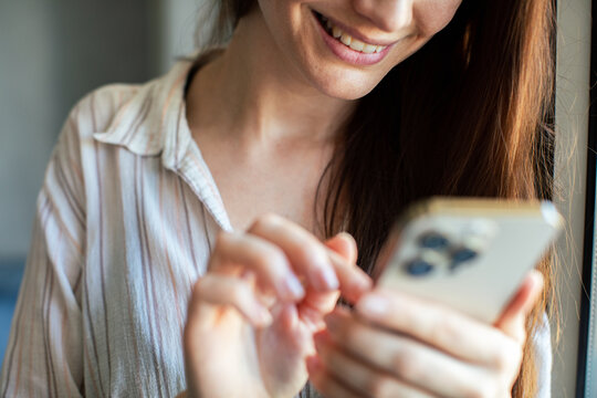 Smiling woman texting on smartphone at home