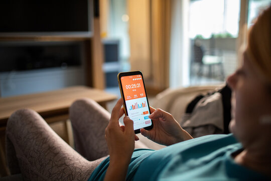 Woman monitoring workout stats on smartphone at home