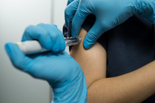 Detailed view of a subcutaneous injection being administered into the deltoid muscle using a modern medical delivery device