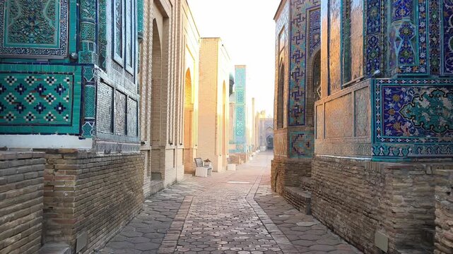 Golden morning light illuminates famous Shah-i-Zinda necropolis. The stone path - stunning turquoise mausoleums, intricate mosaic tiles, medieval Islamic architecture beauty. Samarkand, Uzbekistan.