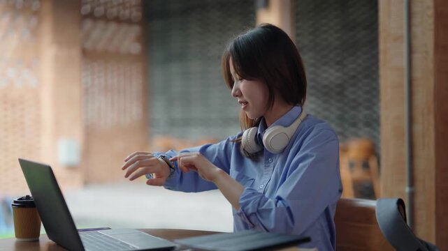 Asian adult woman checking wearable technology device outdoor workspace managing schedule digital life connectivity productivity in modern cafe business casual environment