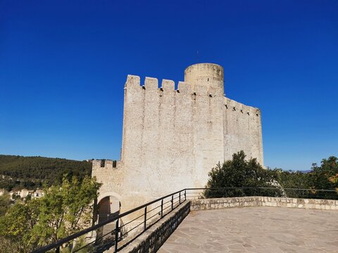 Wide view of Castellet Castle with panoramic terrace and forested background.