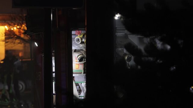 Fire Department truck, hose sleeves, extinguishing fire. Close view firefighting hoses and valves inside emergency vehicle compartment at night, with dark shadows and urban lights.
