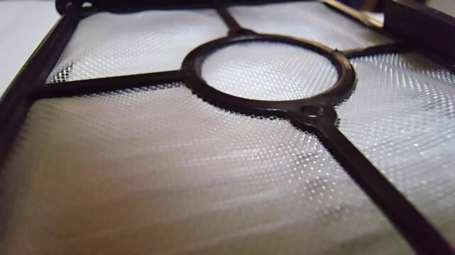 Close-up of a vacuum cleaner mesh filter screen with plastic support frame, highlighting dust filtration, appliance maintenance, and cleaning technology.