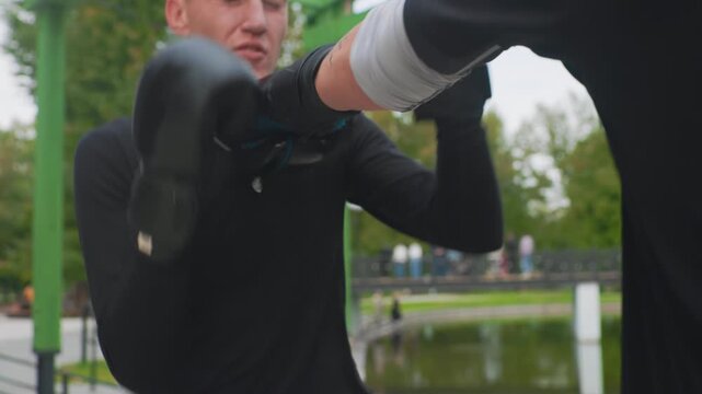 closeup boxer training portrait, caucasian man showing determination. mitt session by pond with coach, quick jabs and hooks, protective guard and sweat, disciplined technique and focused expression,