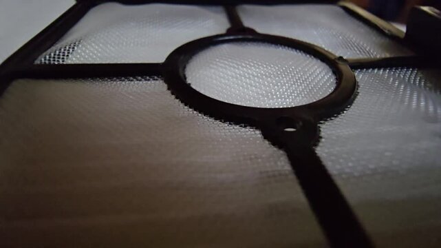 Close-up of a vacuum cleaner mesh filter screen with plastic support frame, highlighting dust filtration, appliance maintenance, and cleaning technology.