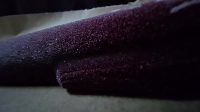 Macro shot of frozen dark berry popsicle featuring intricate ice crystal textures on a wooden stick.
