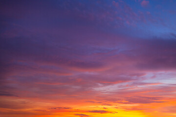 Obraz premium Vibrant Sunset Sky with Rich Orange, Pink, and Purple Clouds,A stunning panoramic photograph capturing the dramatic color palette of a sunset sky. The scene is dominated by a gradient of fiery orange 