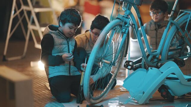 Young boys inflating a bicycle tire with a hand pump