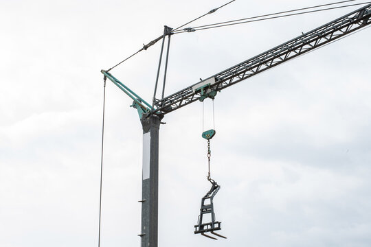 Tower crane lifting construction materials on building site against blue sky, urban development concept