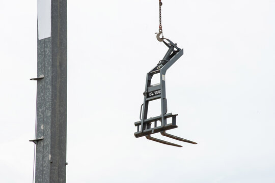 Tower crane lifting construction materials on building site against blue sky, urban development concept