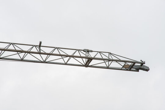 Tower crane lifting construction materials on building site against blue sky, urban development concept