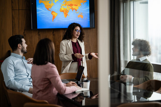 Businesswoman giving global strategy presentation in office meeting
