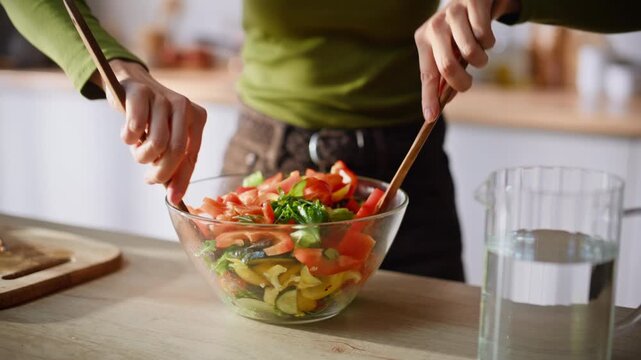 Cook hands mixing salad preparing food at cozy kitchen closeup. Woman cooking