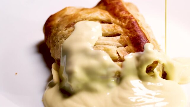 Apple Strudel Being Drizzled with Creamy Vanilla Custard Sauce