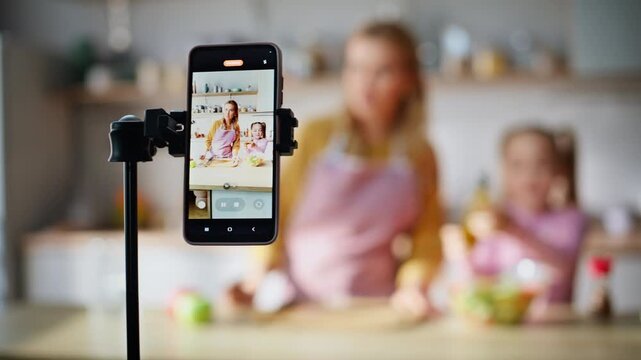 Food vloggers family demonstrating salad to smartphone camera at kitchen closeup