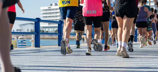 Marathon participants running beside blue railings on waterfront promenade © JairoMZ