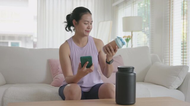 Young gen z active woman drink whey creatine shake bottle eating diet food using phone calorie plan app after home sport workout. health care asia people happy relax protect aging life weight loss.