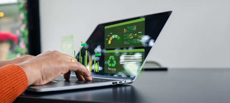 Businesswoman analyzing ESG sustainability data on laptop. Graphic virtual screen showing green energy, recycling, and environmental impact metrics for corporate social responsibility.