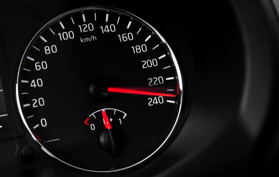Close-up of a car speedometer and dashboard instrument panel showing high speed in km/h, red needle indicating rapid acceleration and performance-focused driving in a dark vehicle interior