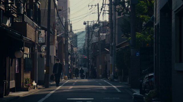 Low angle view of Kyoto neighborhood street with dense wiring and traditional architecture.