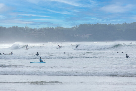 8.12.2025. Weligama Sri Lanka. Crowded surf spot in Weligama bay, Sri Lanka. Group of young people and beginners learning to surf with boards on the beach and in the Indian ocean waves.