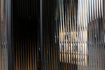 Obraz premium Modern and artistic textured glass panel showcasing a mesmerizing interplay of light and dark vertical lines, ideal for contemporary design elements.